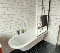 Victorian style free standing bath with black hexagon floor tiles and white metro wall tiles